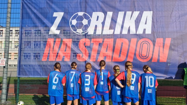 Dziewczęta patrzące na baner z napisem "Z Orlika na Stadion"