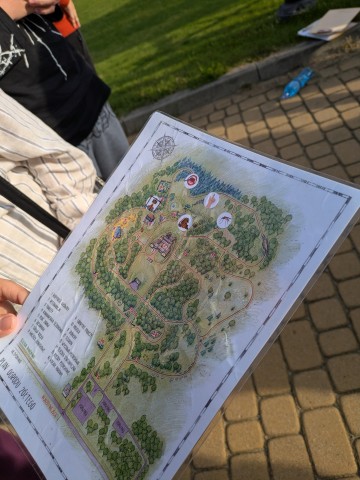 Zdjęcie przedstawia uczestników warsztatów korzystających z mapy Śląskiego Ogrodu Botanicznego w Mikołowie podczas zajęć „Przyrodniczy survival”.