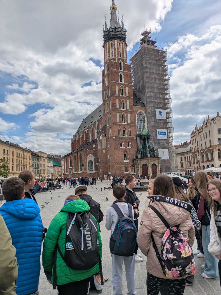 Zdjęcie przedstawia grupę uczniów na krakowskim rynku na tle Kościoła Mariackiego, Kraków 2025